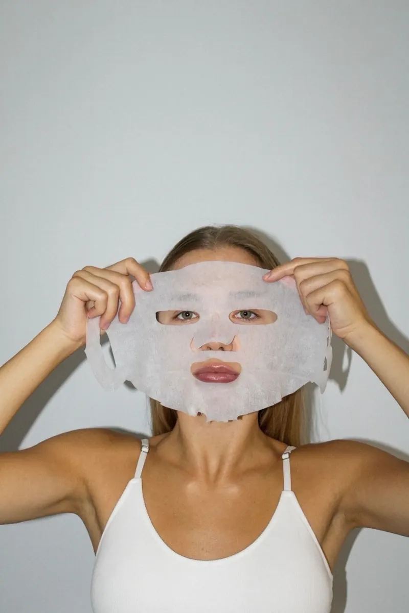 Woman holding a sheet mask in front of her face
